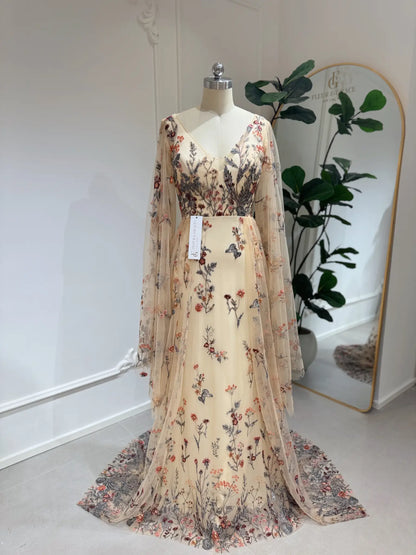 Elva botanical wedding dress with wildflower embroidery, V-neckline, and flowing cape sleeves on a mannequin.