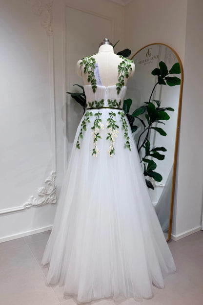 Ivory tulle A-line wedding gown with green leaf and daisy embroidery, sweetheart bodice, and thin green waist belt.