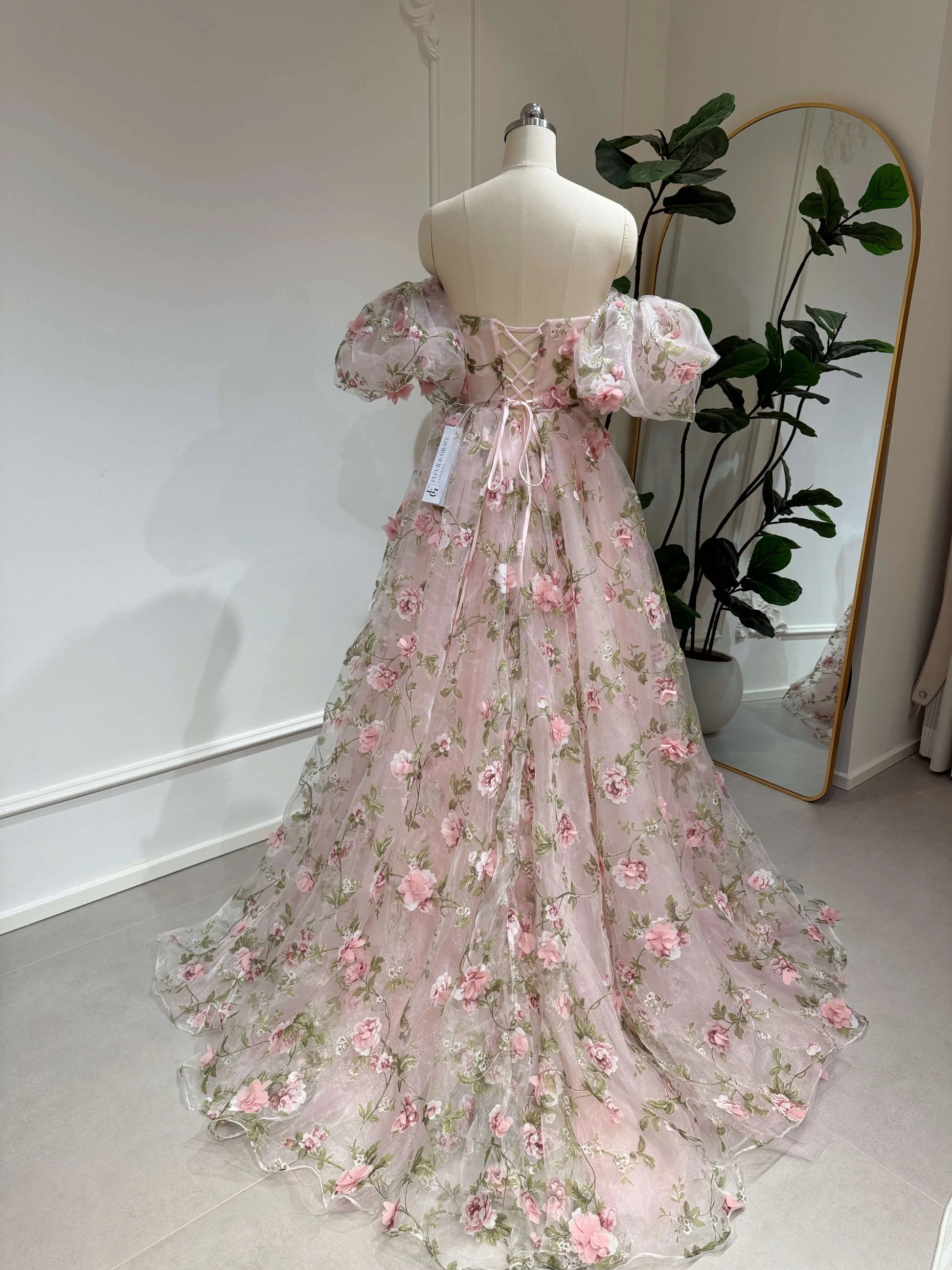 The Pink Rosa Gown FG013 made by Fleur&amp;Grace s a stunning 3D floral lace prom dress designed for elegance and charm. Made with delicate&nbsp;organza lace featuring meadow green leaf prints and sparkly mesh, this gown is perfect for prom, formal events, and photography. The sweetheart neckline and boned bodice provide a structured, flattering fit, while the lace-up back ensures adjustability. Designed with removable short puffy sleeves, pockets, and a side slit, this dress combines beauty and functionali