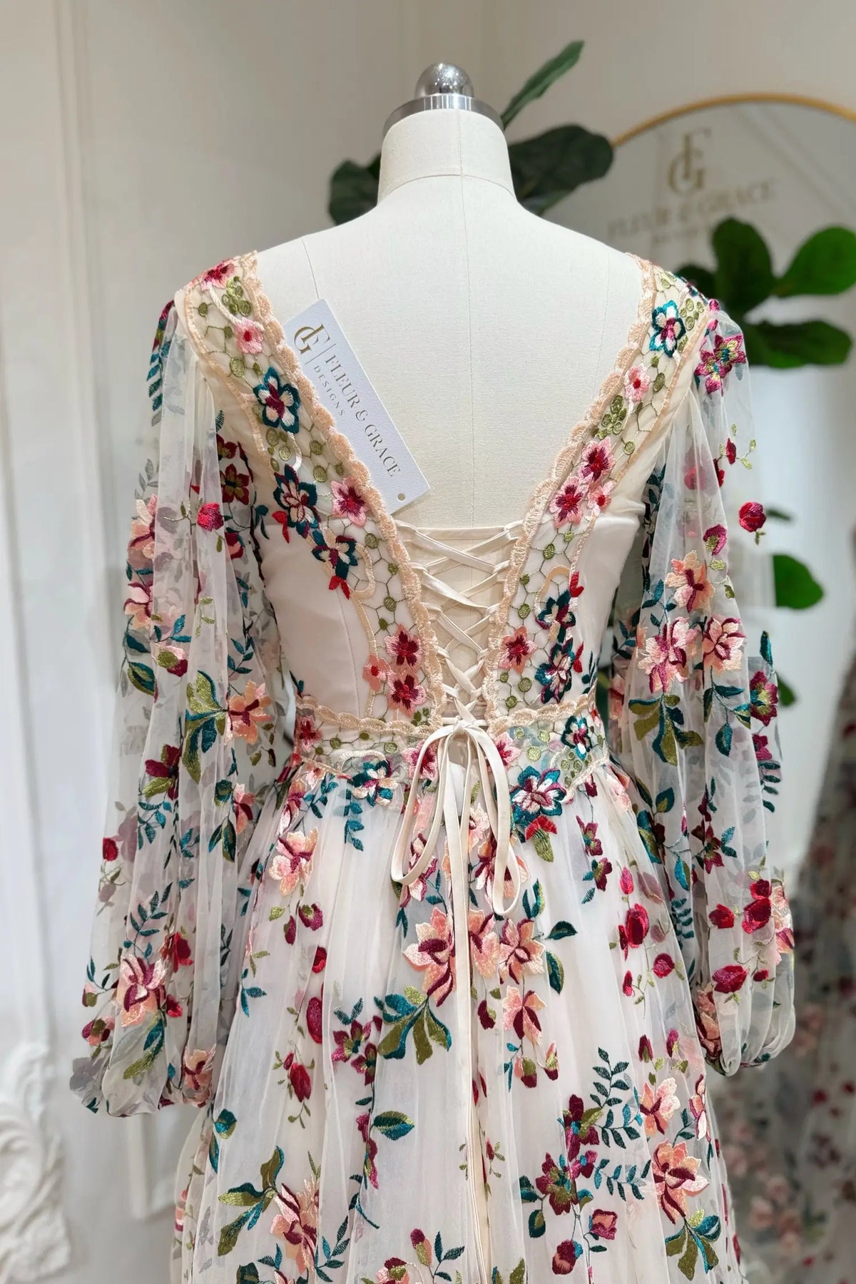 Whimsical A-line wedding dress with colorful floral embroidery, long puff sleeves, and an adjustable lace-up back.