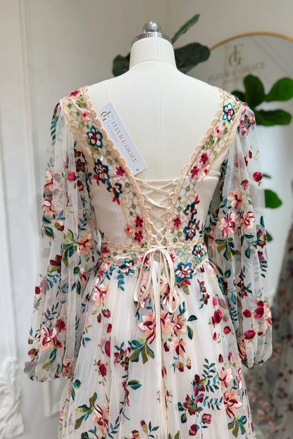 Whimsical A-line wedding dress with colorful floral embroidery, long puff sleeves, and an adjustable lace-up back.