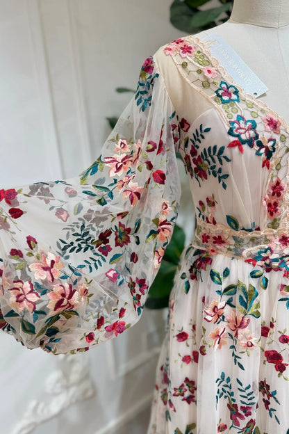 Whimsical wedding dress with long puff sleeves, featuring colorful pink and burgundy floral embroidery on tulle.