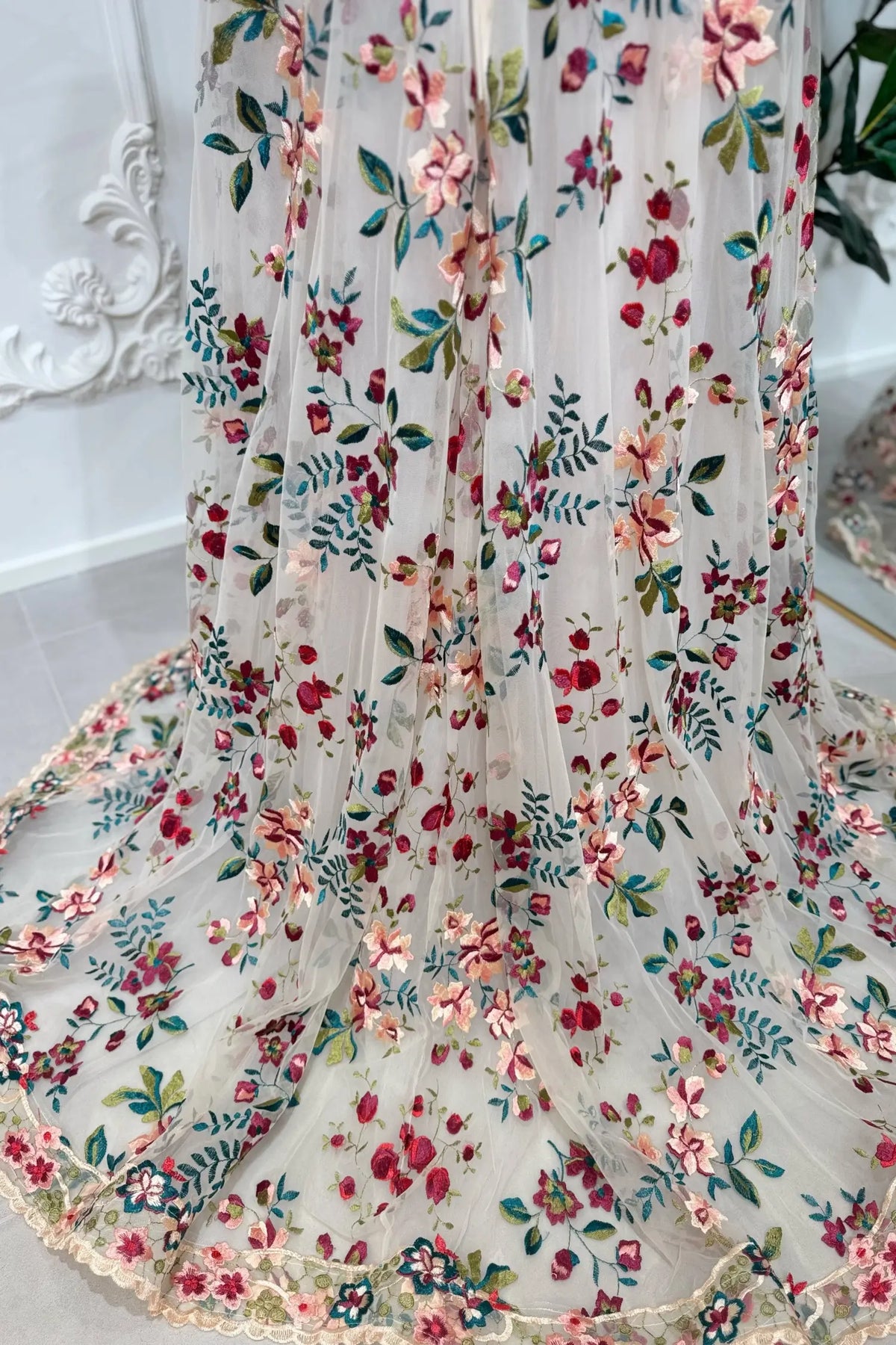 A-line wedding dress with sheer tulle featuring embroidered pink, burgundy, and green floral lace patterns.