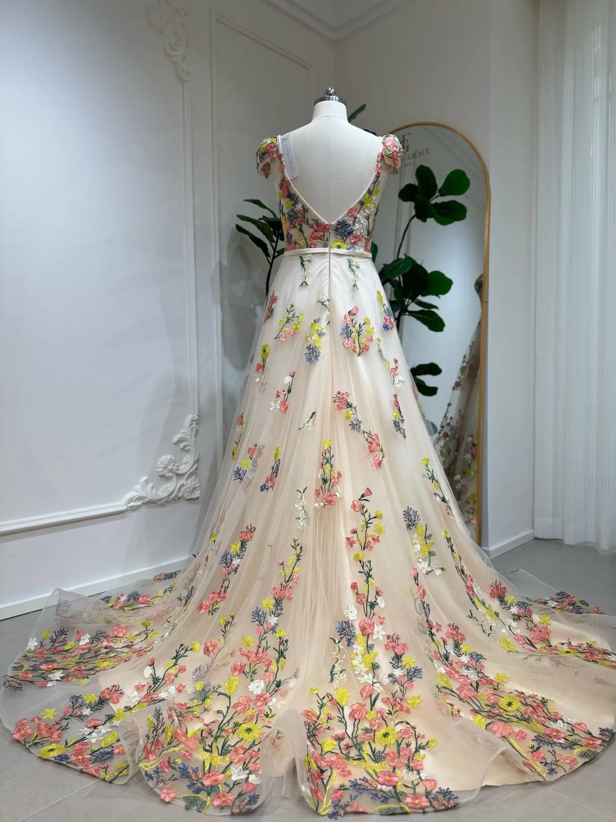 Champagne A-line wedding dress with colorful floral embroidery, cap sleeves, low V-back, and a flowing tulle train.