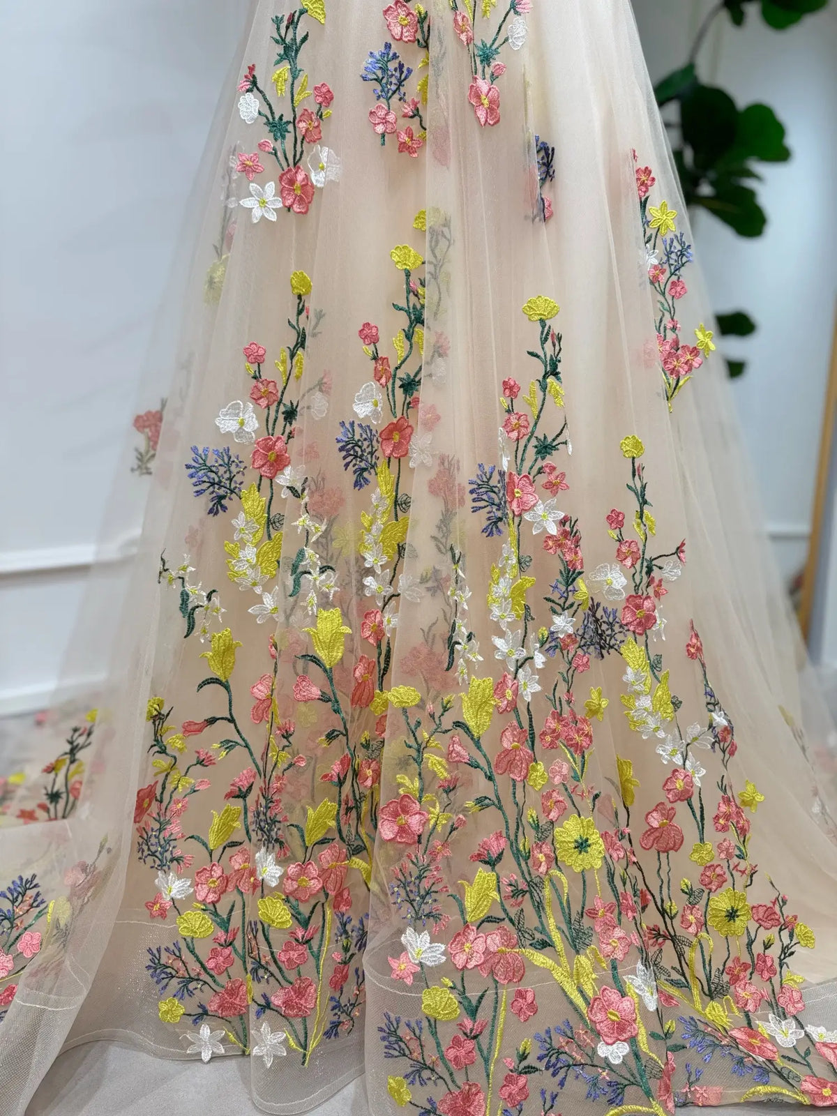 Champagne tulle wedding dress featuring vibrant, hand-embroidered multicolor botanical floral appliqués.
