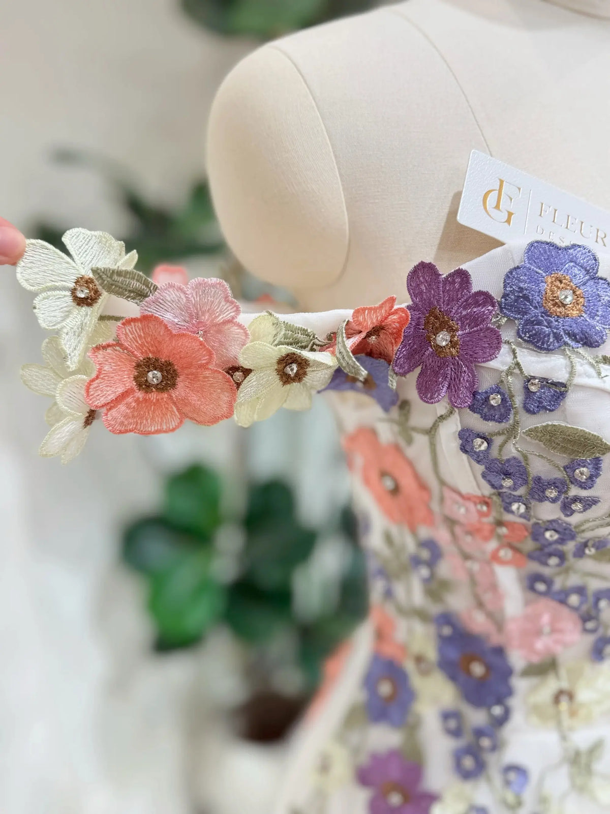 Off-shoulder wedding dress bodice with colorful 3D floral appliqué, beaded accents, and pastel tulle embroidery.