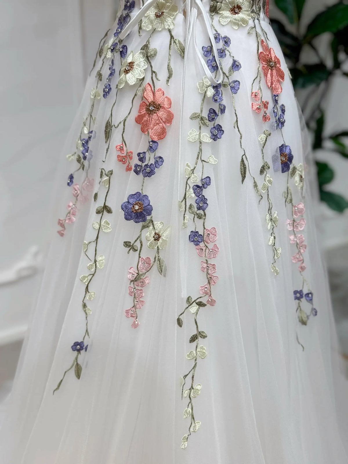 White tulle A-line wedding dress featuring colorful 3D floral embroidery with delicate bead and sequin accents.