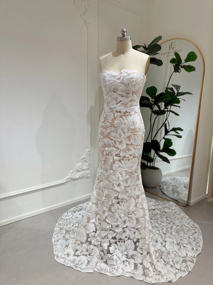 Strapless mermaid wedding dress with floral embroidered lace, glitter sequins, and a chapel-length train on a mannequin.