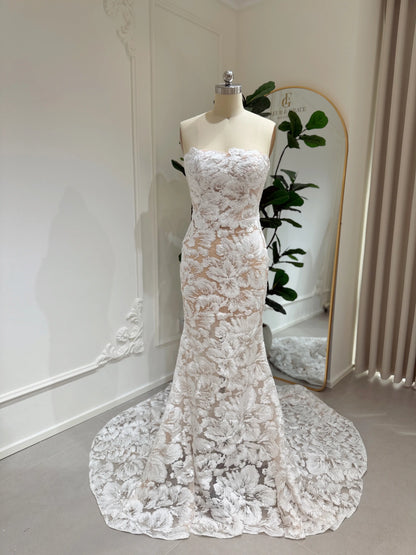 Strapless mermaid wedding dress with white floral embroidery, glitter sequins, and a chapel-length train on a mannequin.