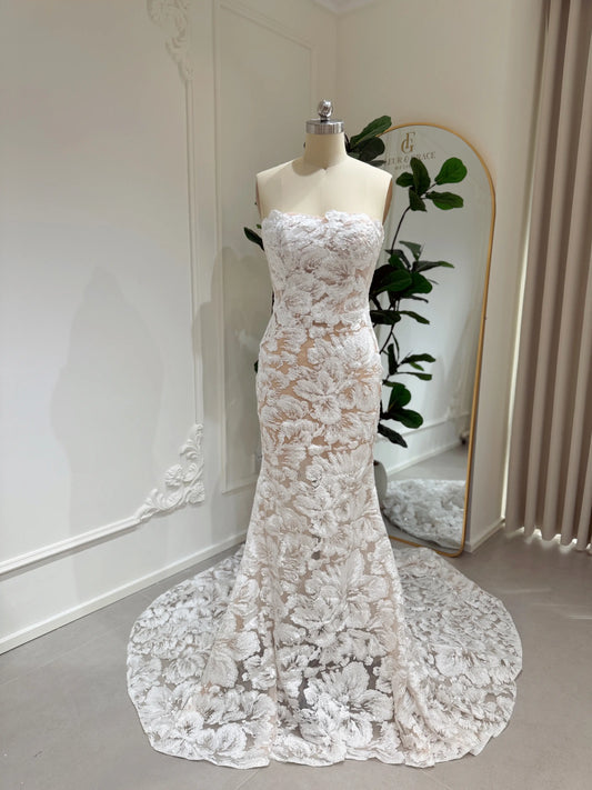 Strapless mermaid wedding dress with white floral embroidery, glitter sequins, and a chapel-length train on a mannequin.