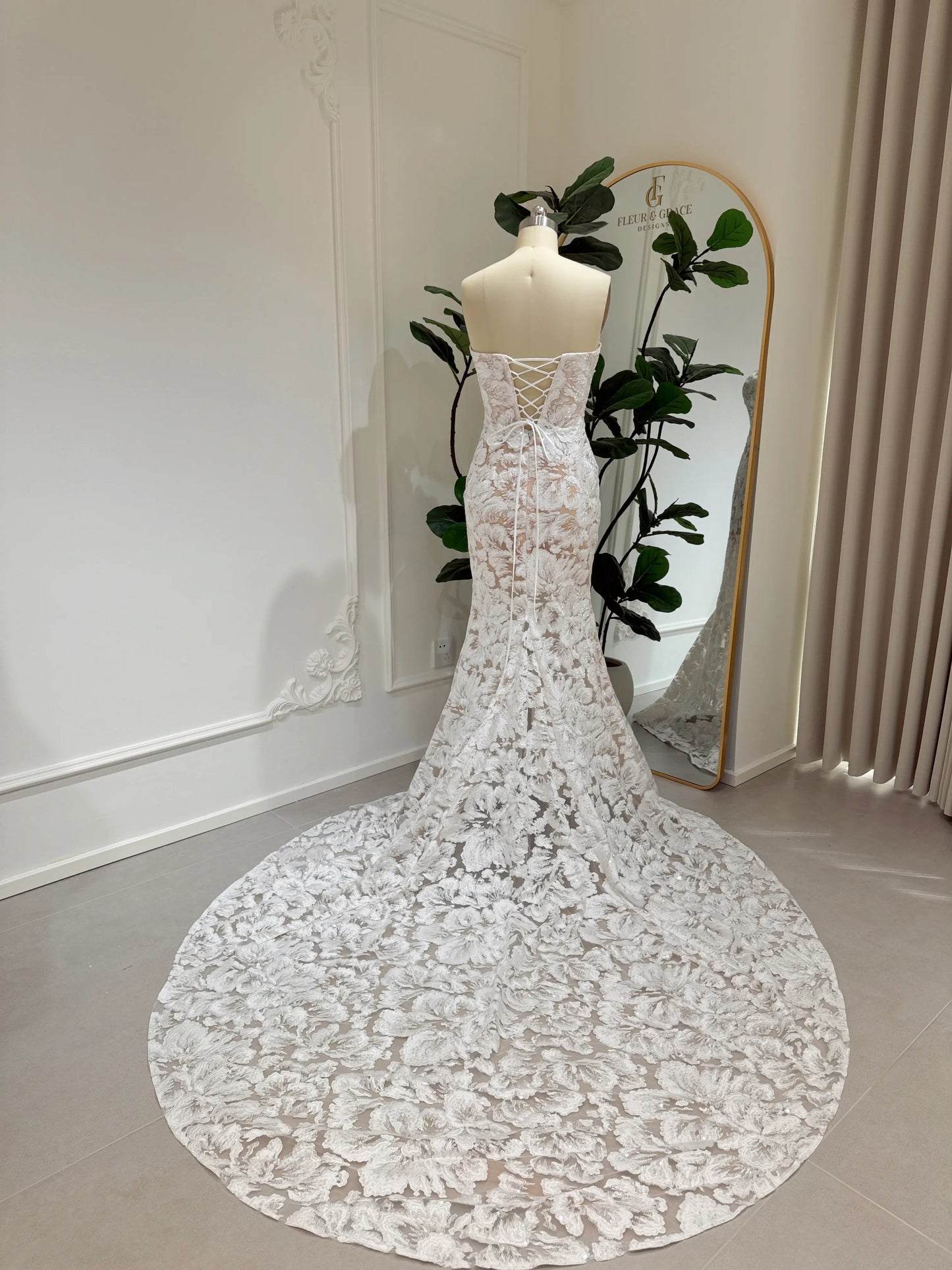 Mannequin wearing the Jane Gown by Fleur&Grace Designs – strapless mermaid wedding dress with floral embroidered lace, glitter sequins, lace‑up back, and chapel‑length train.