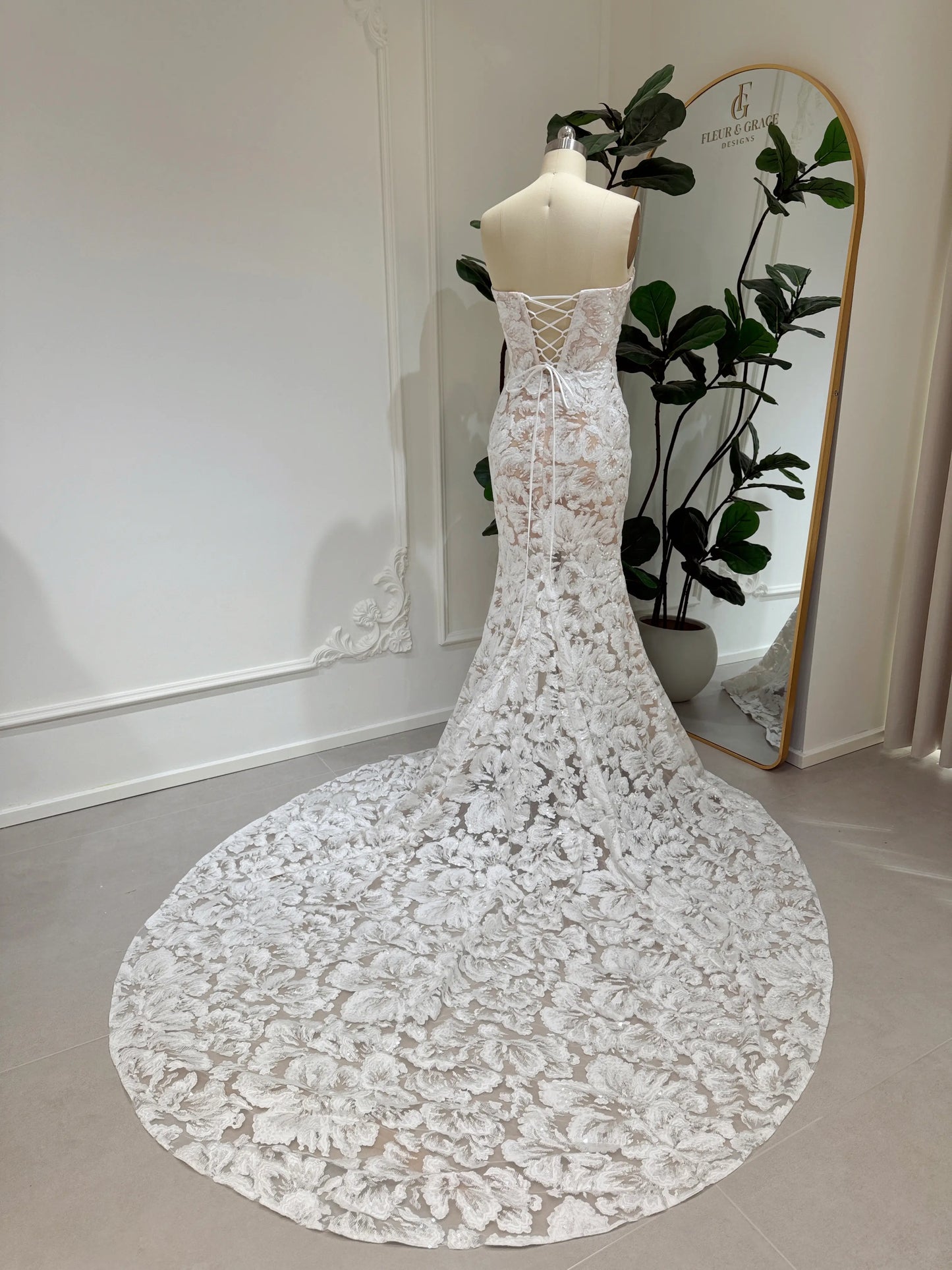 Mannequin wearing the Jane Gown by Fleur&Grace Designs – strapless mermaid wedding dress with floral embroidered lace, glitter sequins, lace‑up back, and chapel‑length train.