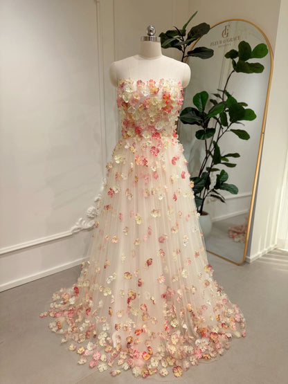 Pink strapless floor-length wedding gown featuring 3D floral appliqués on a structured bodice and tulle skirt.