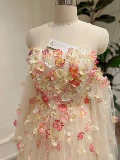 Pink strapless wedding gown featuring 3D floral appliqués, a structured bodice, and sheer removable sleeves on a mannequin.