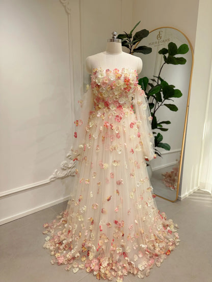 Pink floor-length wedding gown with 3D floral appliqués, strapless bodice, and sheer removable sleeves on a mannequin.