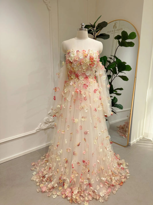 Pink floor-length wedding gown with 3D floral appliqués, strapless bodice, and sheer removable sleeves on a mannequin.