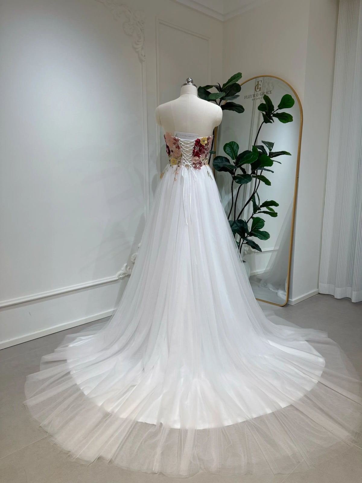 Strapless fairy wedding dress with a colorful floral sequin bodice, lace-up back, and flowing blush pink tulle train.