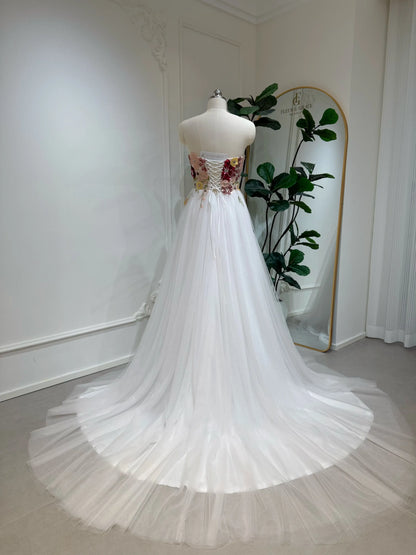 Strapless fairy wedding dress with a colorful floral sequin bodice, lace-up back, and flowing blush pink tulle train.
