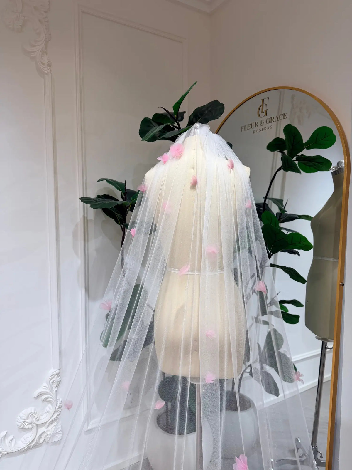 Cathedral-length bridal veil in soft illusion tulle featuring handmade blush pink 3D flowers on a mannequin.