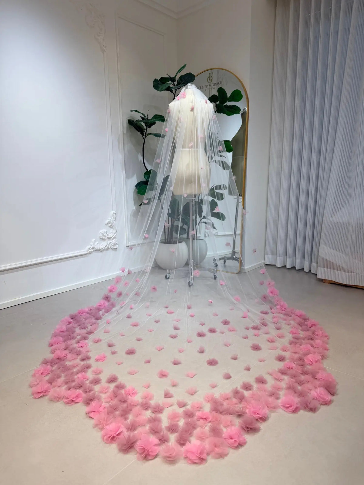 Cathedral-length bridal veil in soft illusion tulle featuring handmade blush pink 3D flowers on a mannequin.