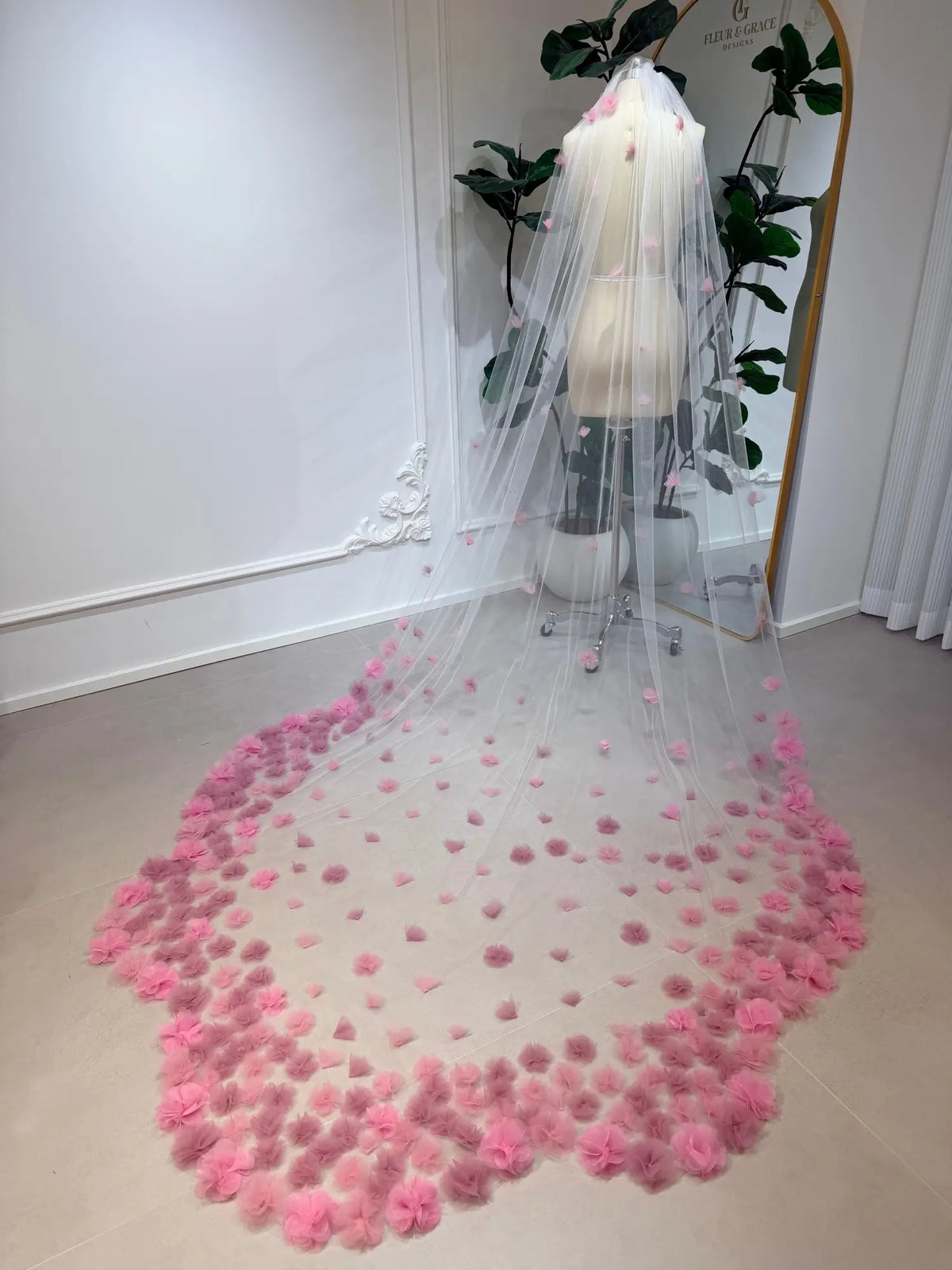 Cathedral-length bridal veil in soft illusion tulle featuring handmade blush pink 3D flowers on a mannequin.