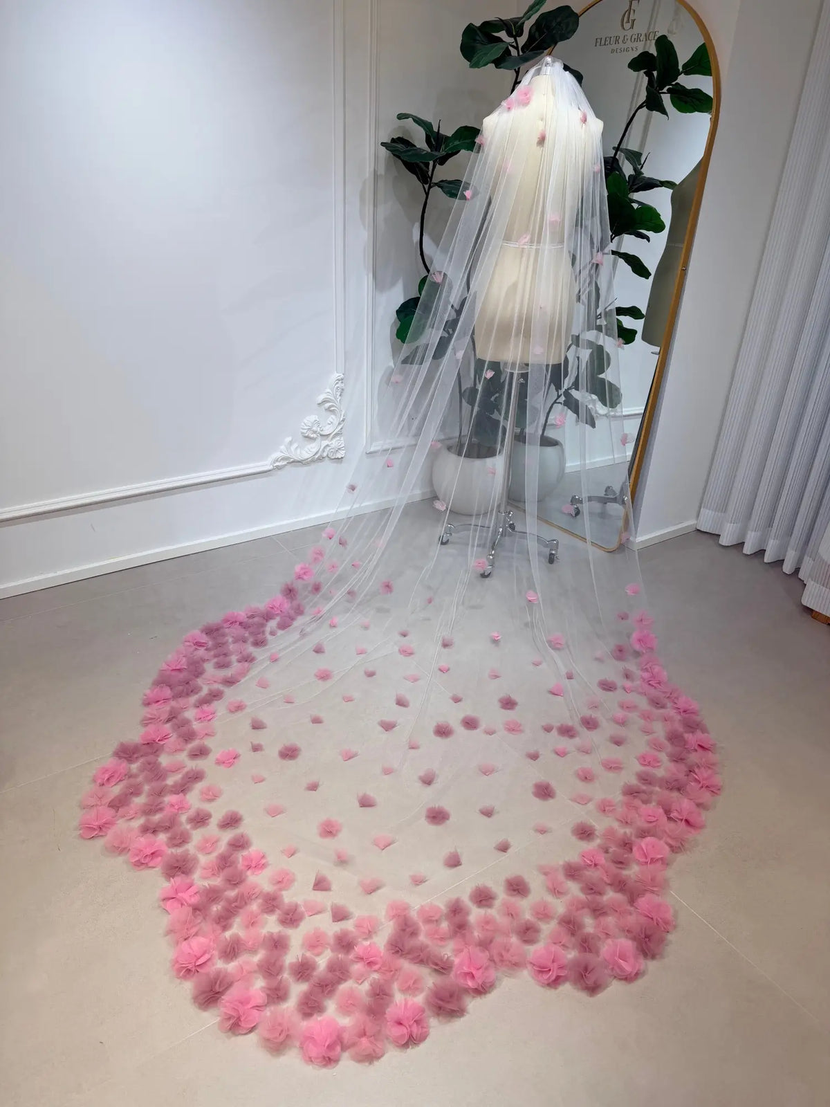 Cathedral-length bridal veil in soft illusion tulle featuring handmade blush pink 3D flowers on a mannequin.