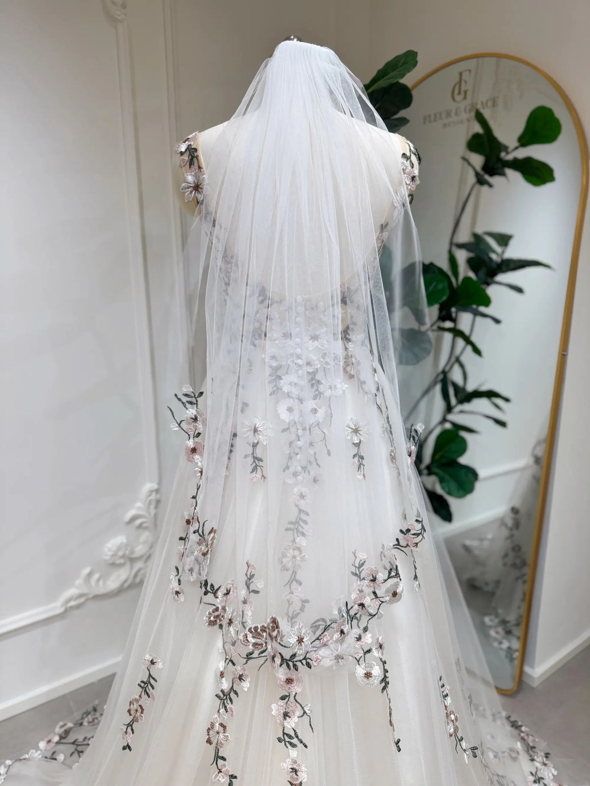 Backless champagne tulle wedding gown with colorful floral embroidery, sleeveless bodice, and matching veil.