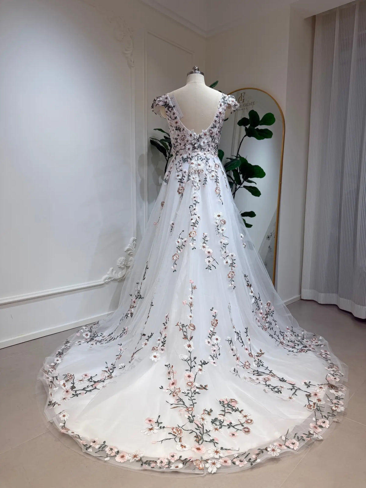 A-line wedding gown with cap sleeves, featuring 3D floral embroidery on white tulle and a graceful chapel train.