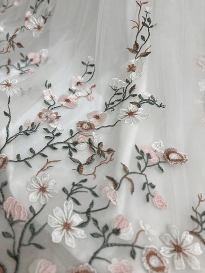 Bride mannequin wearing the Kate Gown by Fleur&Grace Designs – white tulle wedding dress with meadow floral embroidery, V‑neckline, lace‑up back, pockets, and chapel‑length train.