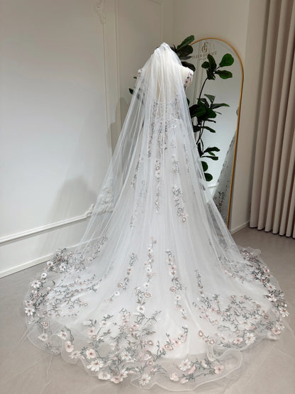 Bride mannequin wearing the Kate Gown by Fleur&Grace Designs – white tulle wedding dress with meadow floral embroidery, V‑neckline, lace‑up back, pockets, and chapel‑length train.