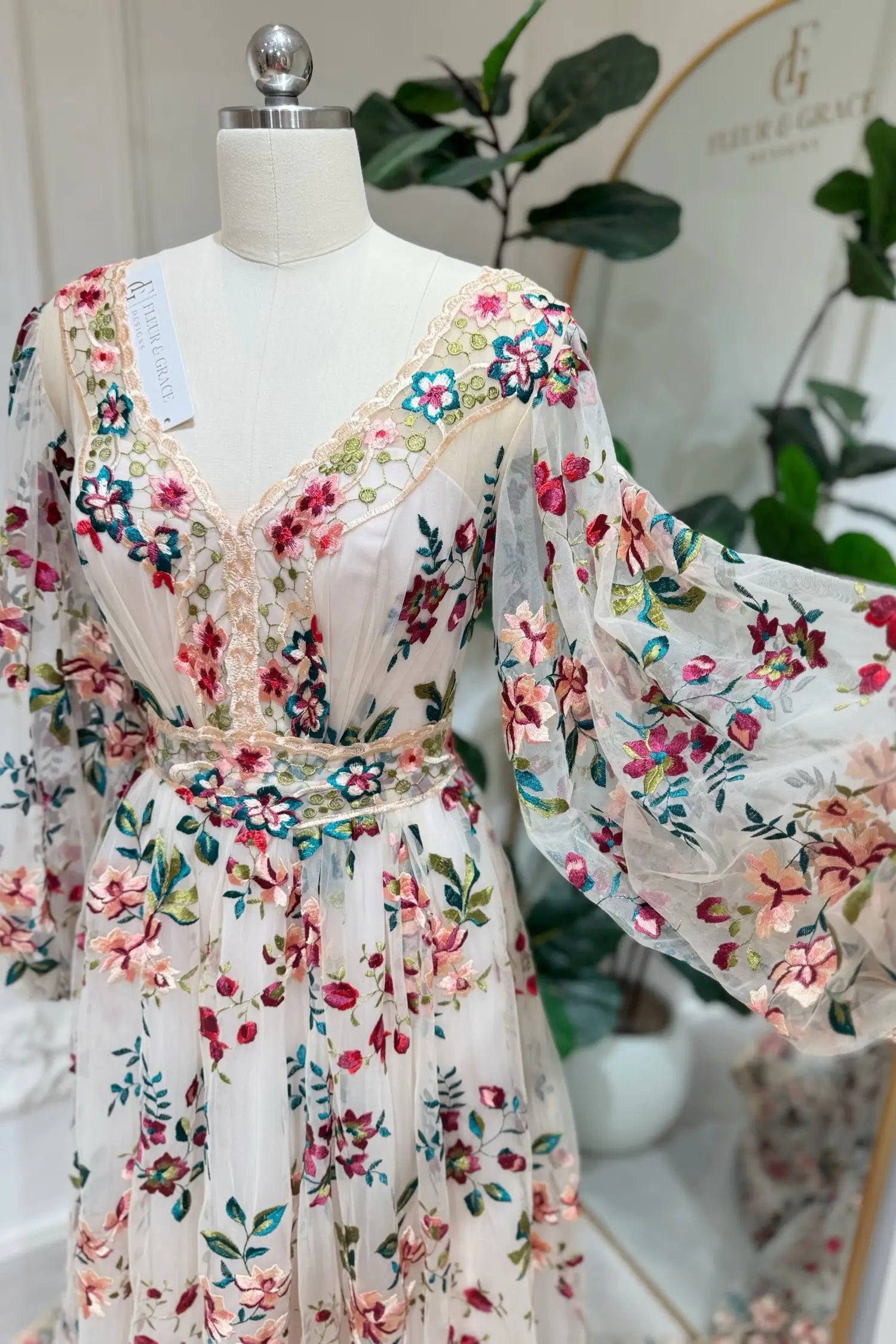 Ferry Gown by Fleur&Grace Designs — whimsical colorful floral wedding dress with pink and burgundy embroidery, long puff sleeves, lace-up back, invisible pockets, and sweep train for forest or elopement weddings.