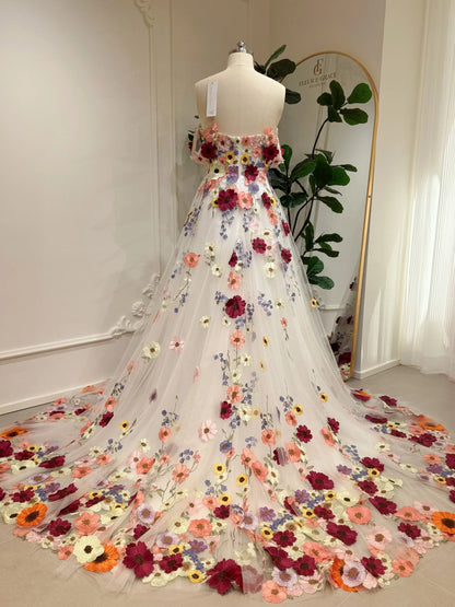 Amber Gown by Fleur&Grace Designs — off-white tulle wedding dress with colorful floral embroidery, off-the-shoulder neckline, plunging V-neck, hidden pockets, and chapel-length train for whimsical and garden weddings.