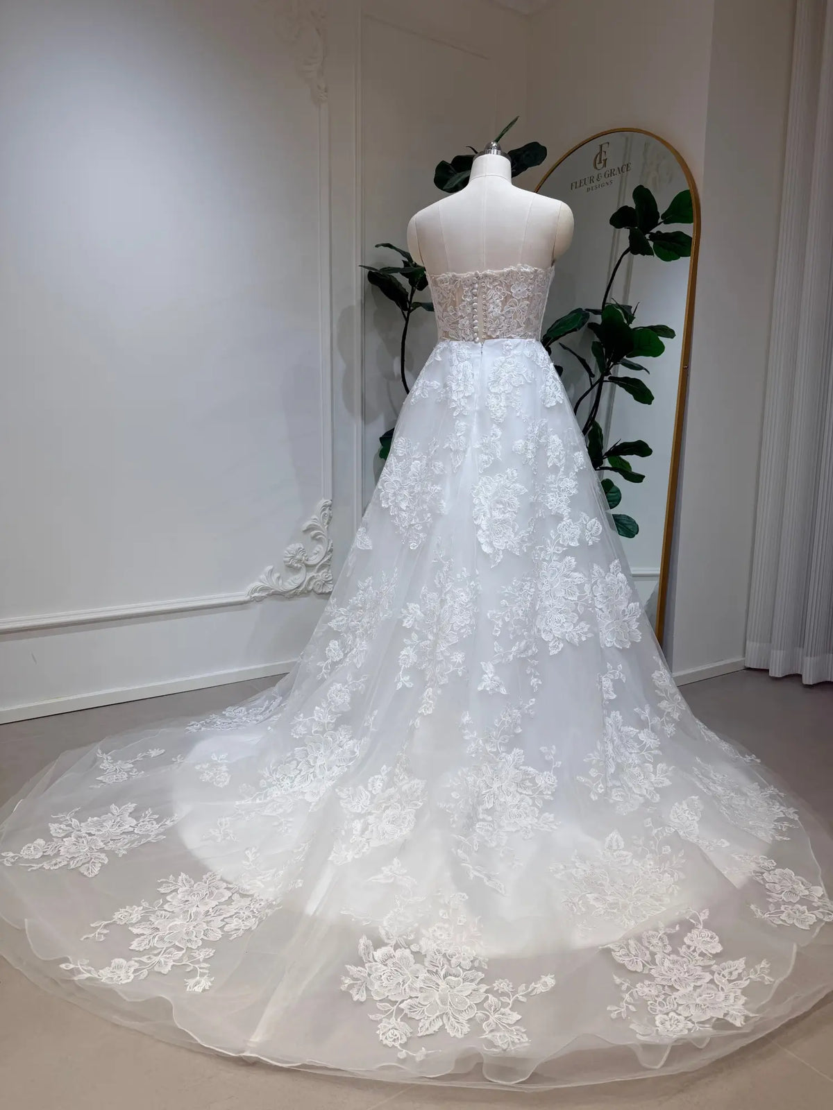 Strapless A-line wedding dress with floral lace appliqués, a fitted bodice, and a flowing tulle chapel train.