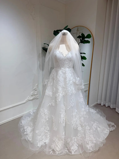 Strapless A-line wedding dress with floral lace appliqués, tulle skirt, and matching veil on a mannequin.