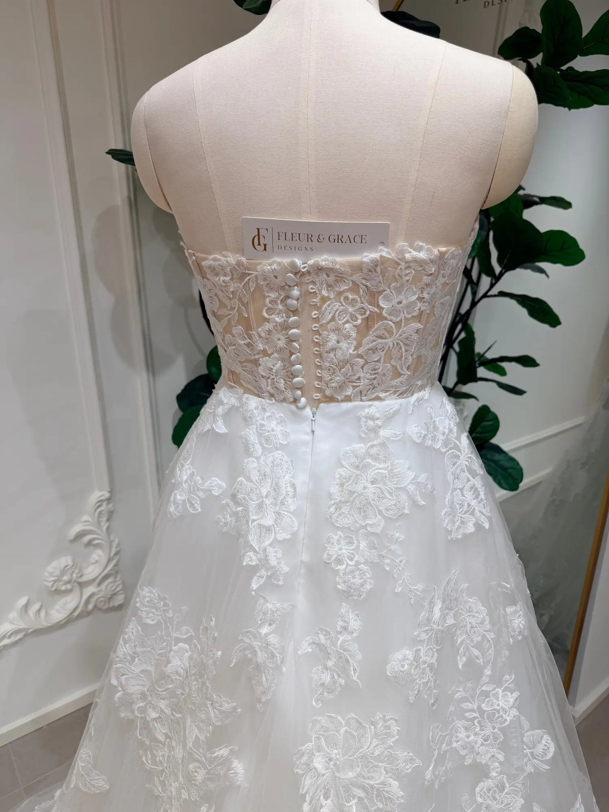 Strapless A-line wedding dress with floral lace bodice, illusion back, and delicate button-down detailing.