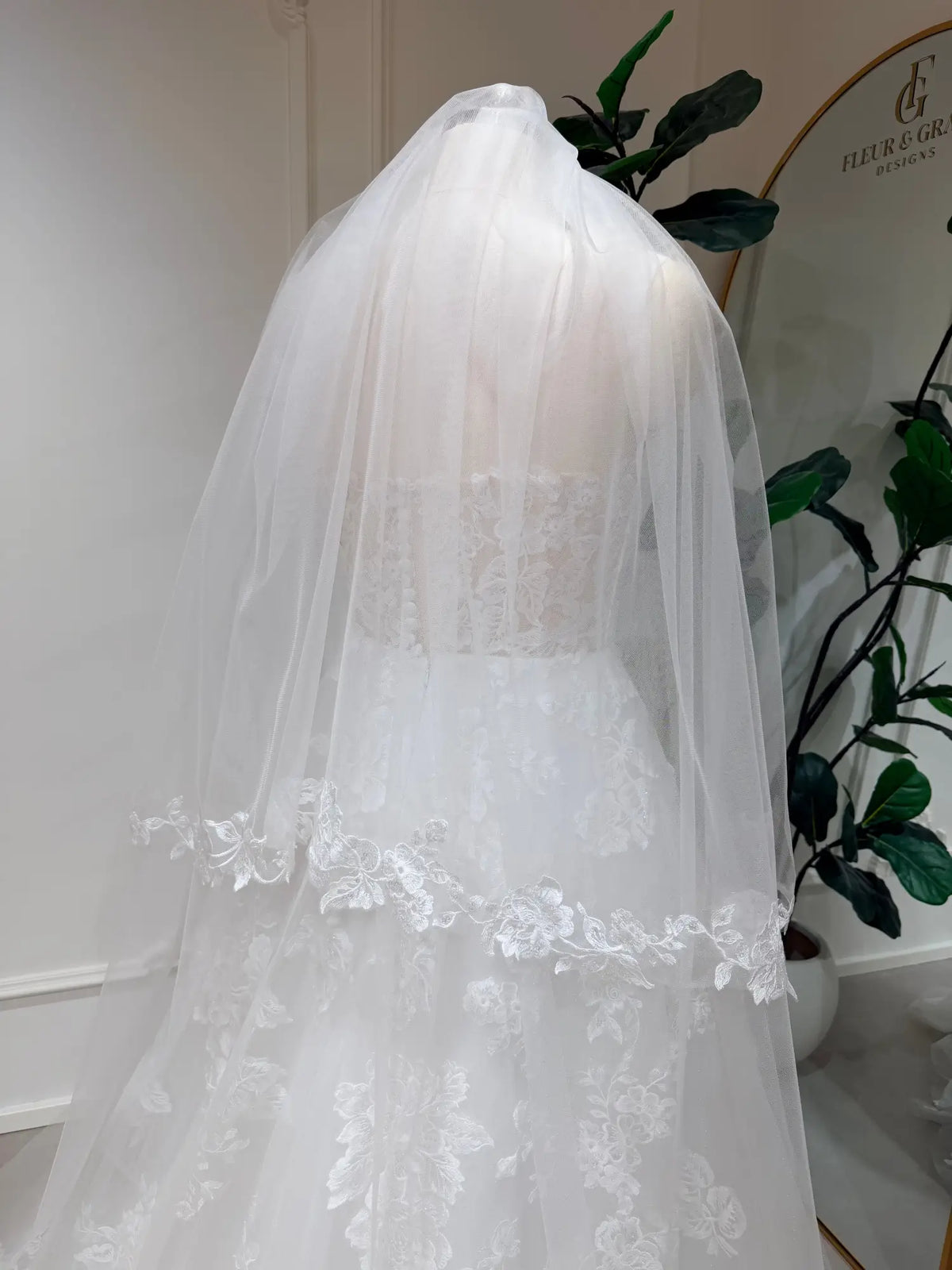 Cathedral-length white bridal veil in soft illusion tulle with delicate floral lace edging on a mannequin.
