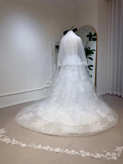 Cathedral-length white bridal veil in soft illusion tulle with delicate floral lace edging on a mannequin.