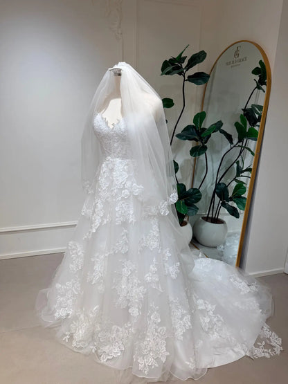 Cathedral-length white bridal veil in soft illusion tulle with delicate floral lace edging on a mannequin.