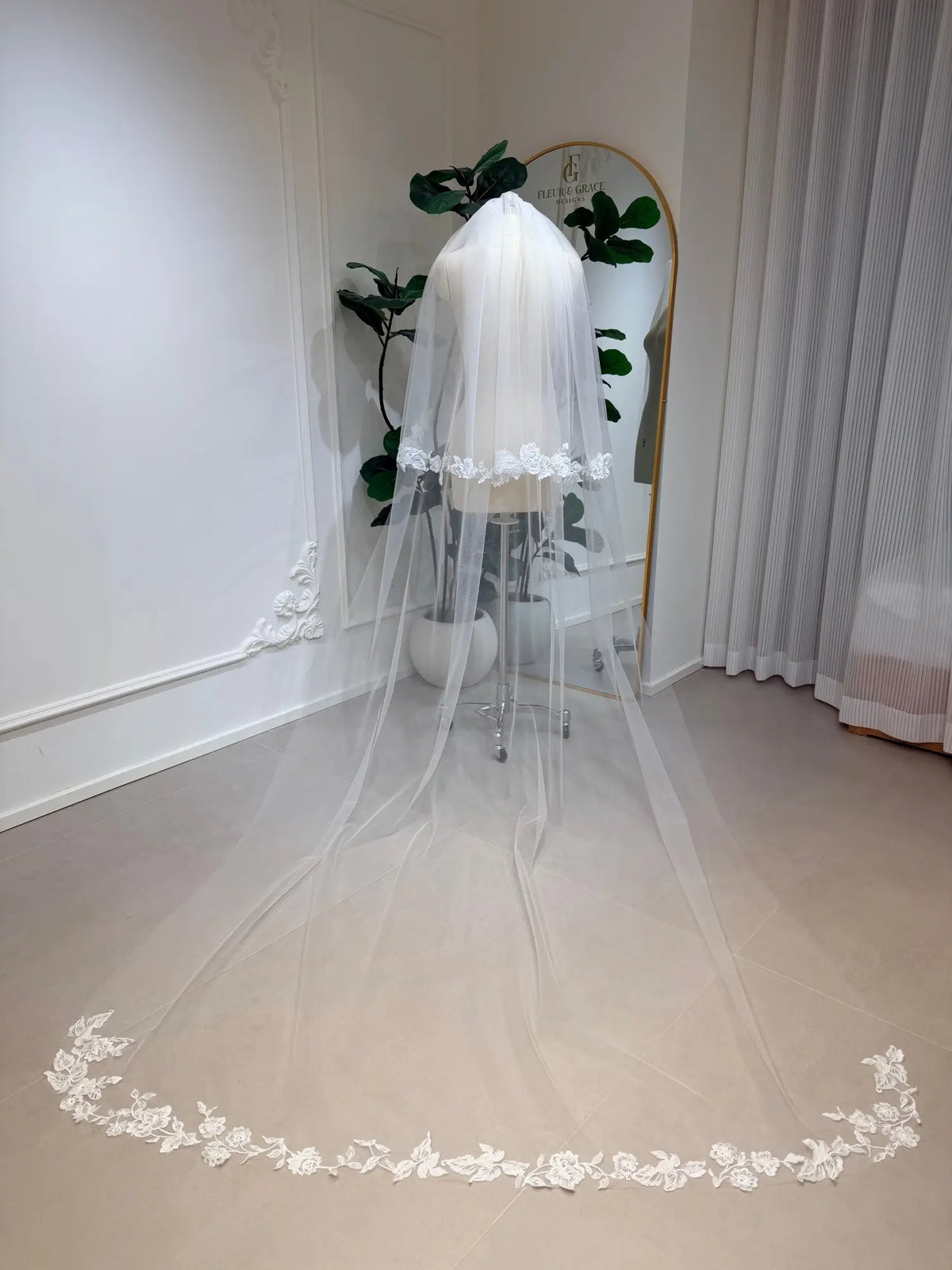 Cathedral-length white bridal veil in soft illusion tulle with delicate floral lace edging on a mannequin.