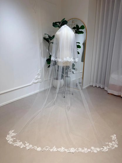 Cathedral-length white bridal veil in soft illusion tulle with delicate floral lace edging on a mannequin.