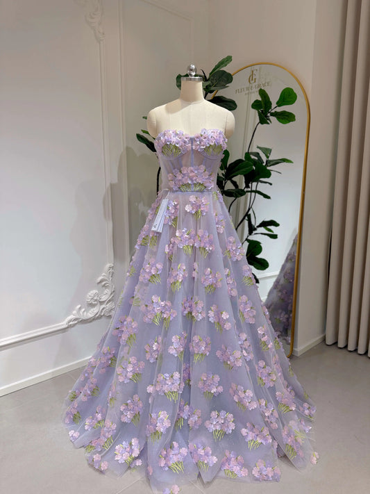 Lavender floor-length prom gown with 3D hydrangea floral lace, sweetheart neckline, and shimmering mesh overlay on a mannequin.