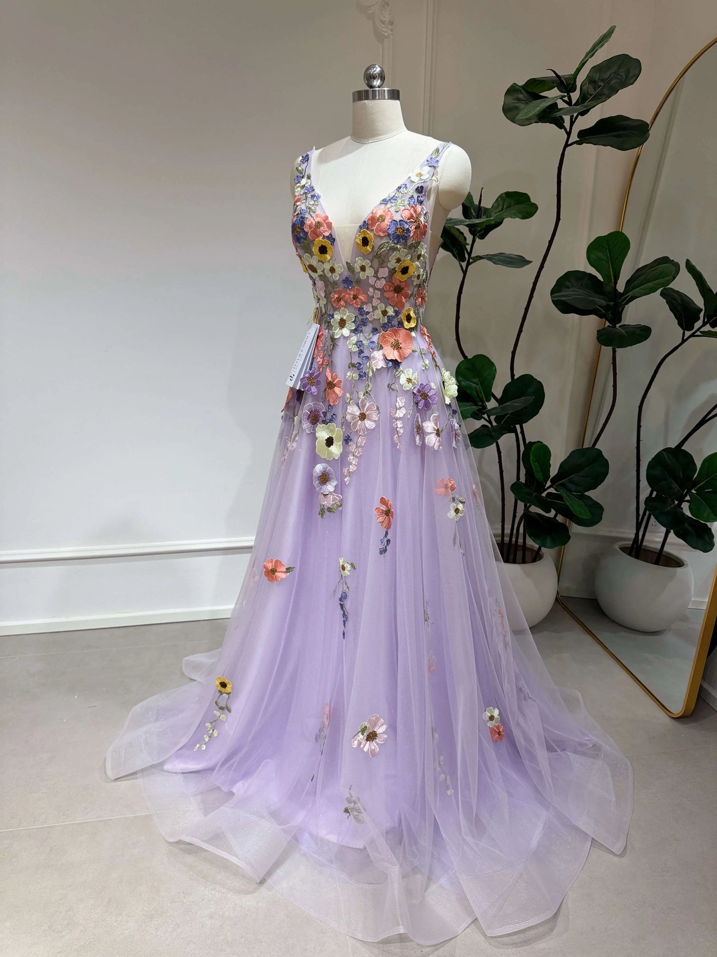 Lavender V-neck formal gown with sparkly tulle, floral embroidery, and a structured bodice on a mannequin.