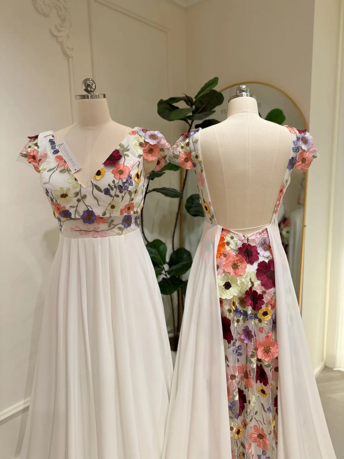Chiffon A-line wedding dress with floral embroidered bodice, cap sleeves, and a dramatic open back with floral panel.