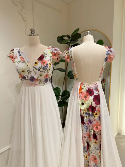 Chiffon A-line wedding dress with floral embroidered bodice, cap sleeves, and a dramatic open back with floral panel.