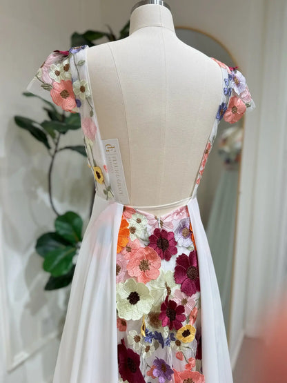 Open-back chiffon wedding dress with vibrant floral embroidery on the bodice and a cascading botanical back panel.