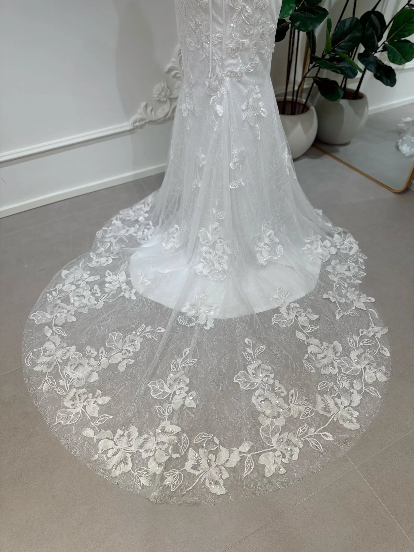 Bridal mannequin wearing the Lena Gown FG030 by Fleur&Grace Designs—a mermaid lace wedding dress with off-the-shoulder sleeves, sheer boned bodice, corset back, basque waistline, asymmetric hemline, and chapel-length train.