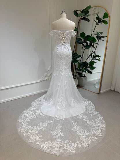 Off-the-shoulder mermaid wedding dress with intricate lace, corset back, and a dramatic chapel-length train.