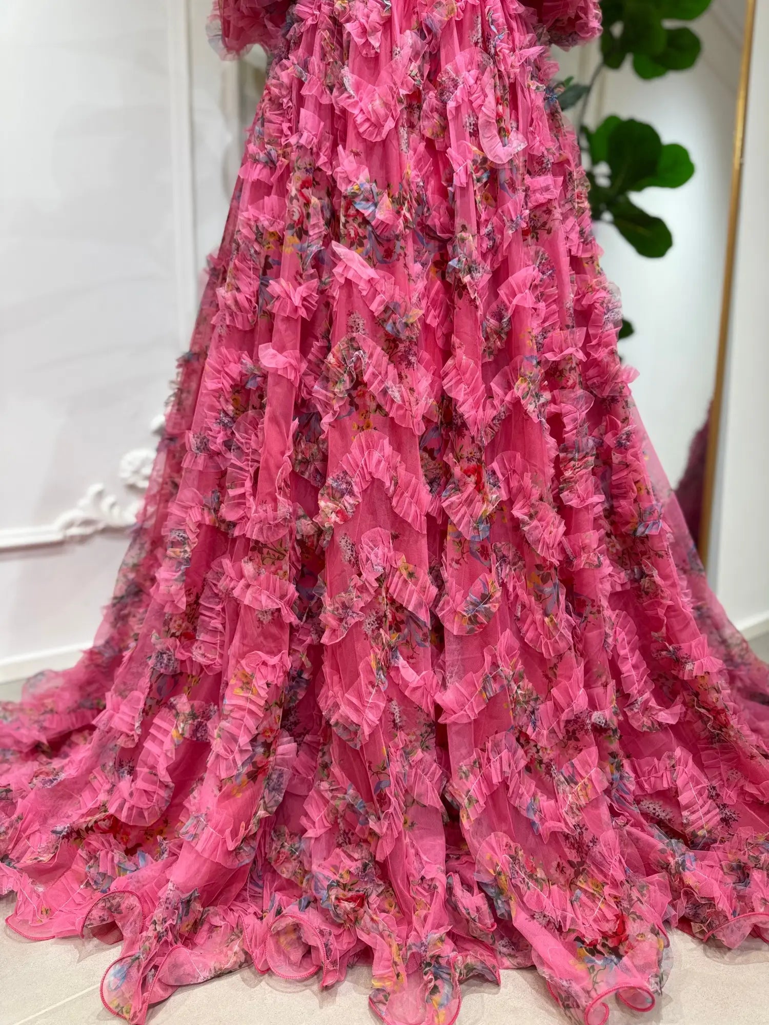 Pink floral tulle gown featuring cascading ruffles, puff sleeves, and a voluminous A-line skirt for formal occasions.