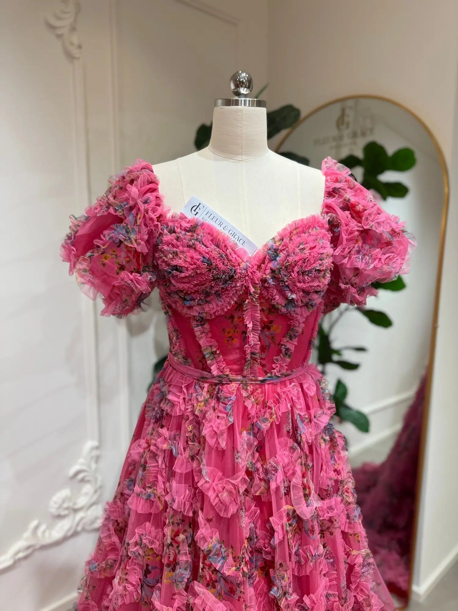Pink floral tulle gown with off-the-shoulder puff sleeves, sweetheart corset bodice, and cascading ruffle details.