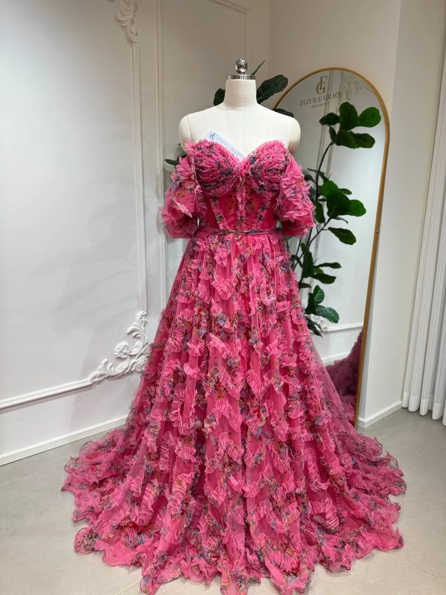 Pink floral tulle gown with off-the-shoulder puff sleeves, sweetheart corset bodice, and cascading ruffled A-line skirt.